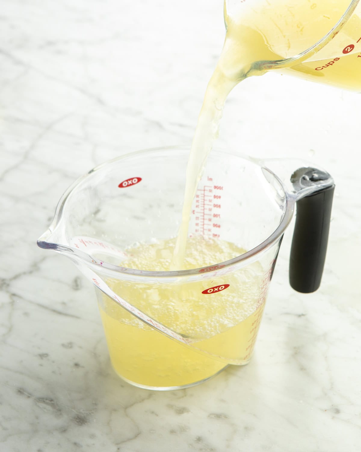 Lemonade being mixed together in measuring cup. 