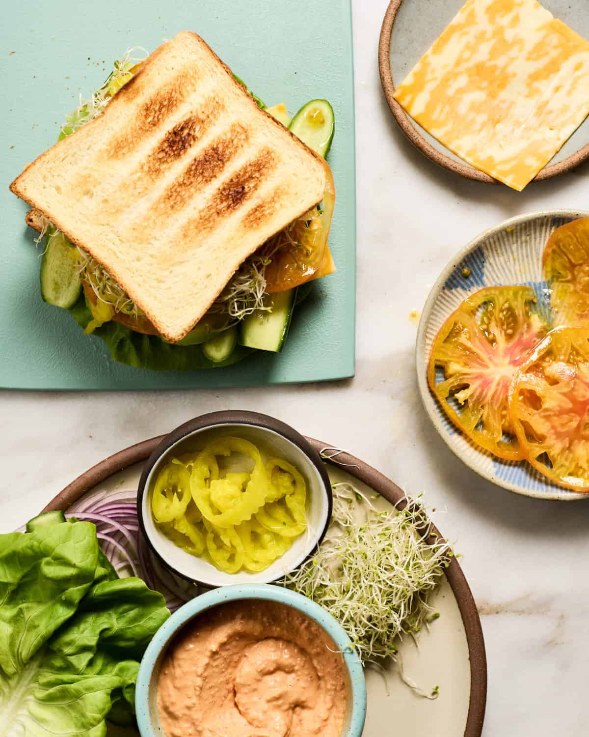 Veggie Sandwich on a cutting board with toppings all around.