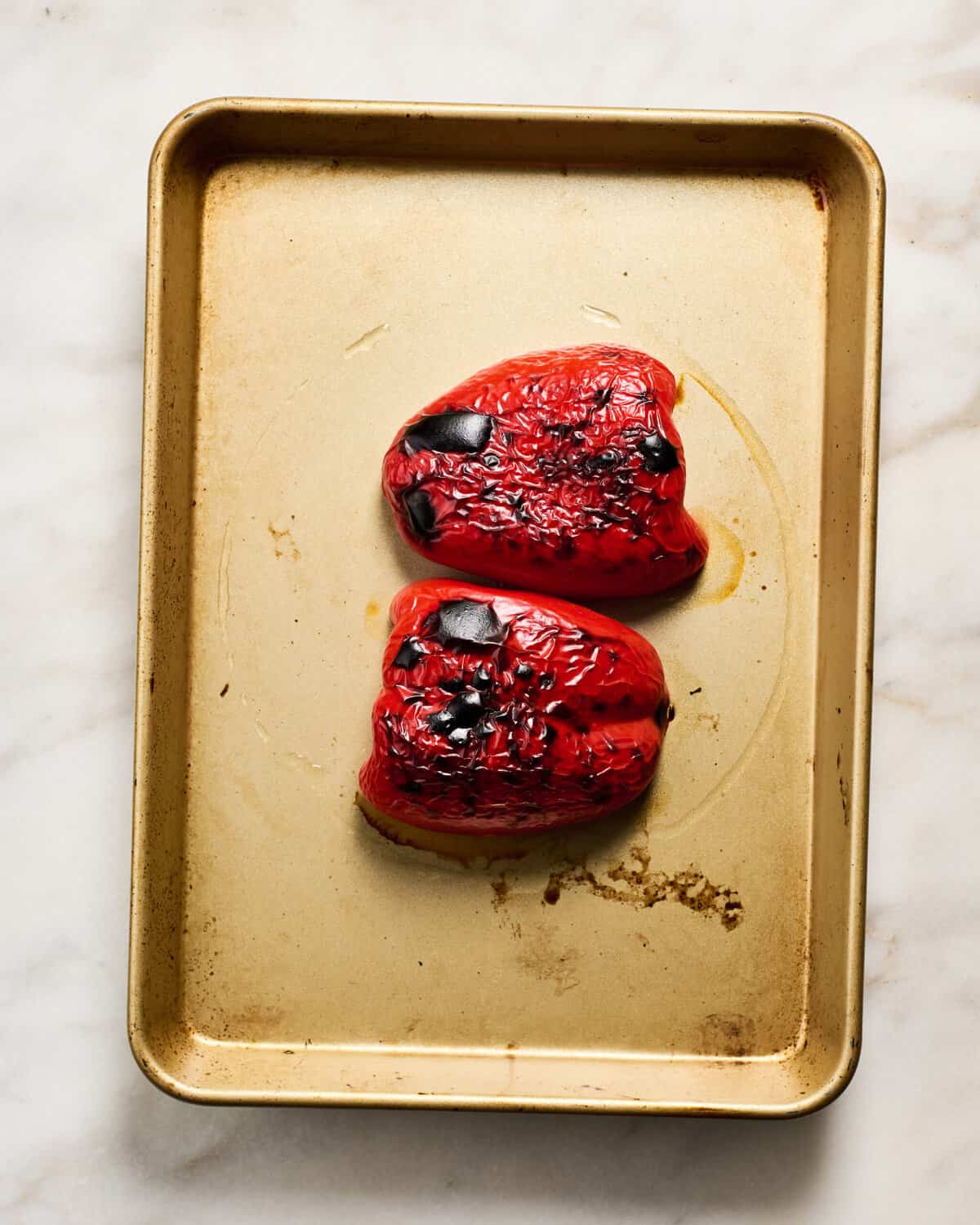 Charred red bell pepper on a baking sheet.