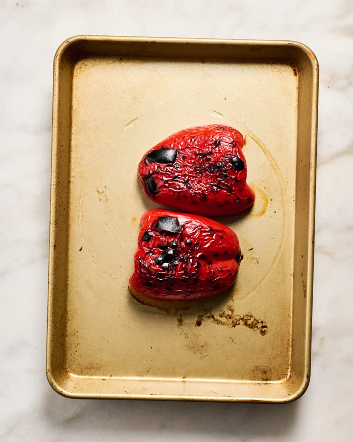 Charred red bell pepper on a baking sheet. 