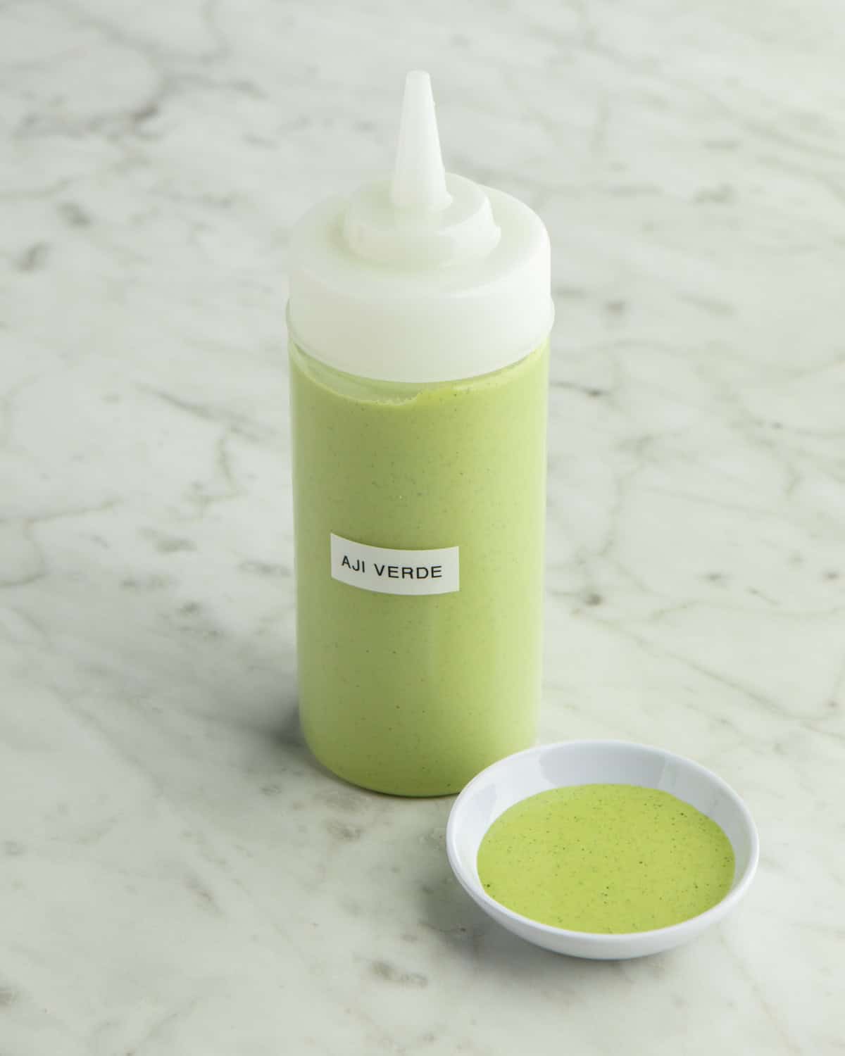 Squeeze bottle of Aji Verde with a dish on the side. 