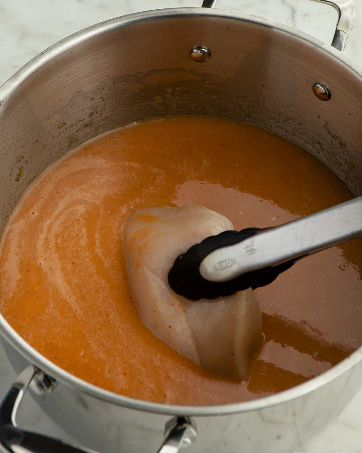 Chicken going into broth in pot.