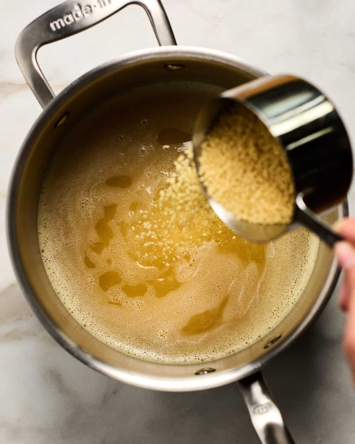 Pastina being added to a pot.