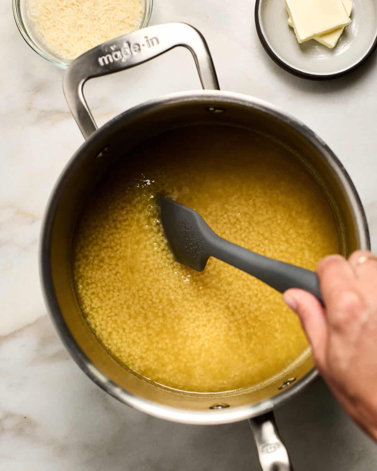 Pastina being stirred in a pot.