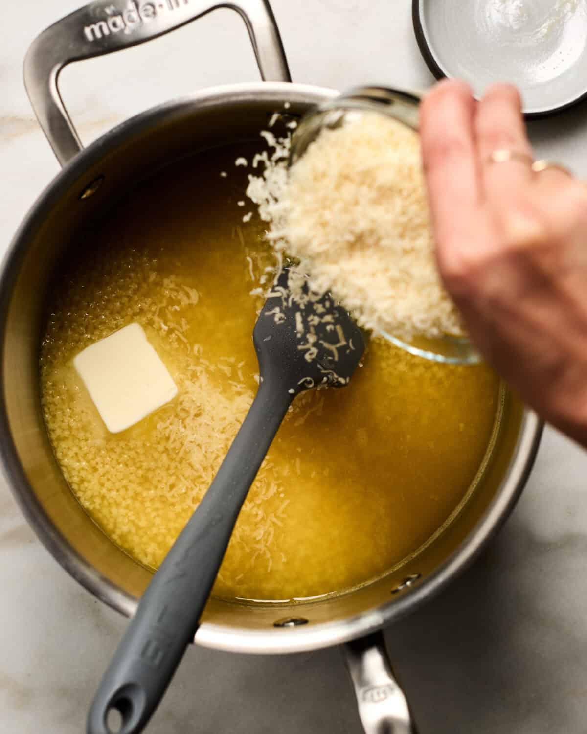 Parmesan-Reggiano being added to a pot.