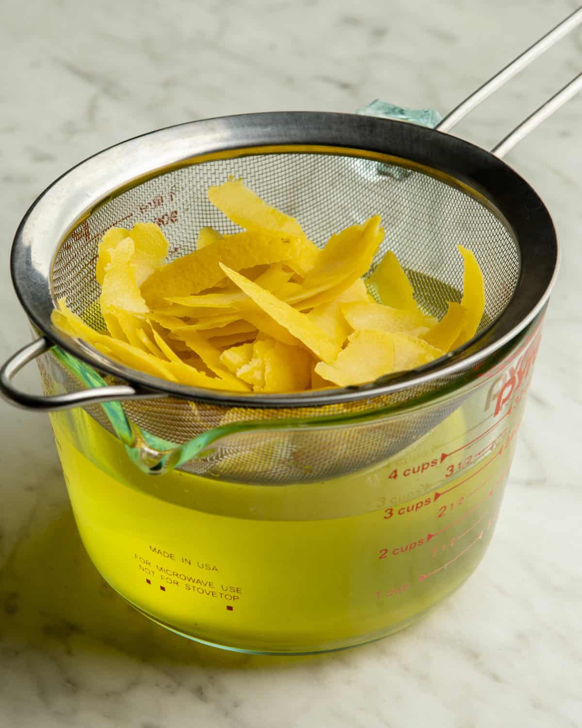 Straining lemon peels from liquid.