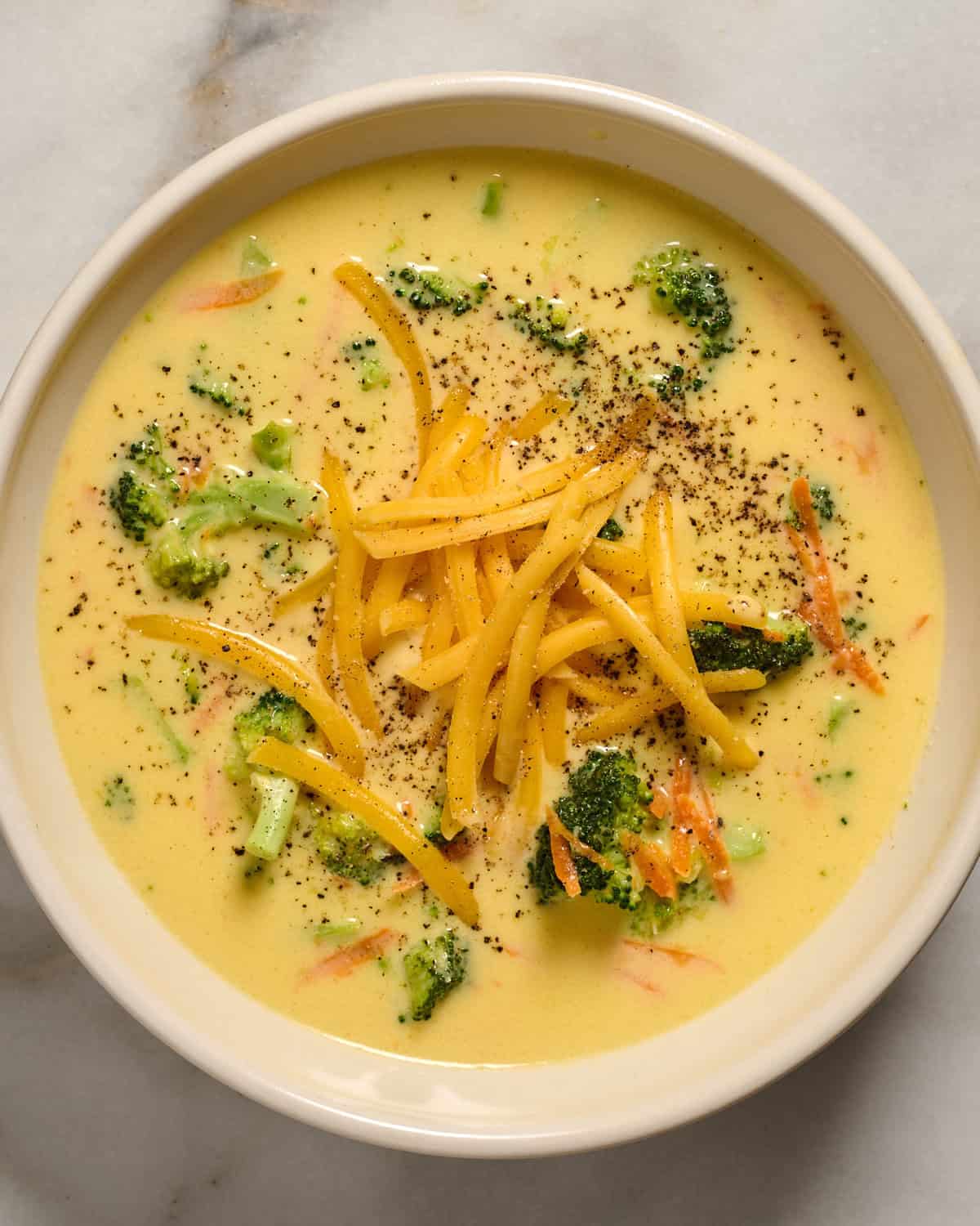 Bowl of broccoli cheddar soup with cheese on top.