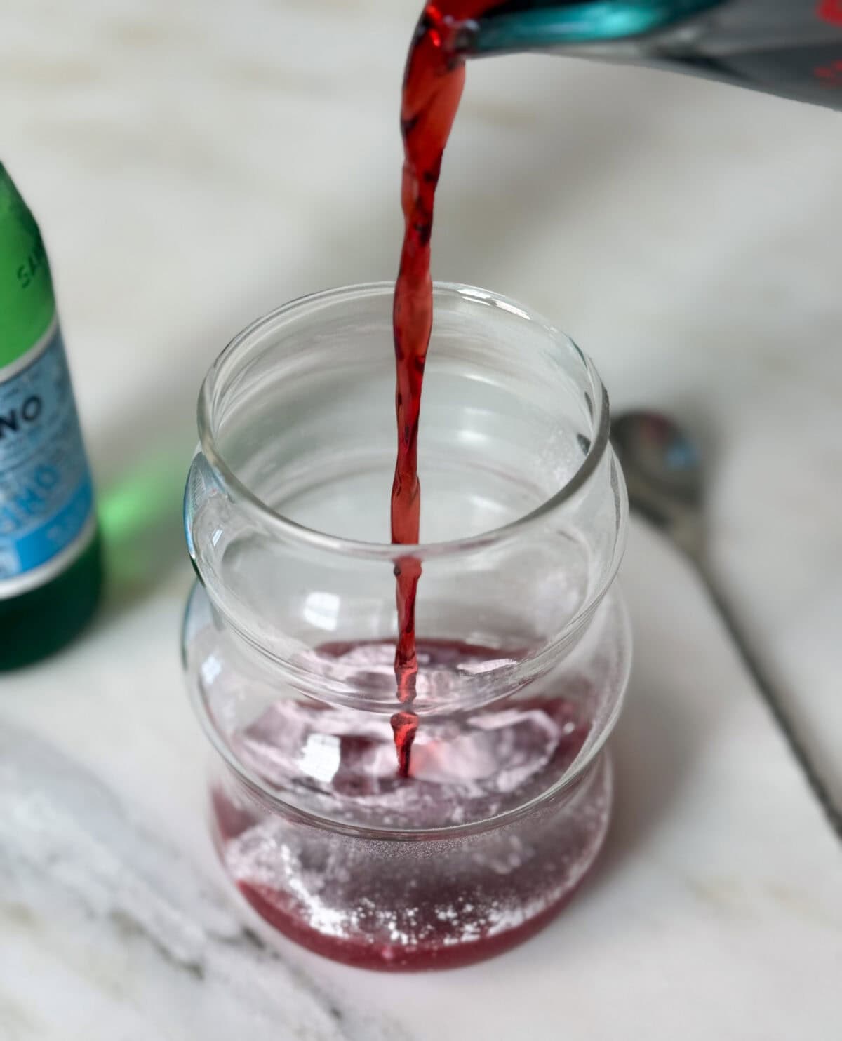 Cherry juice being poured in glass. 