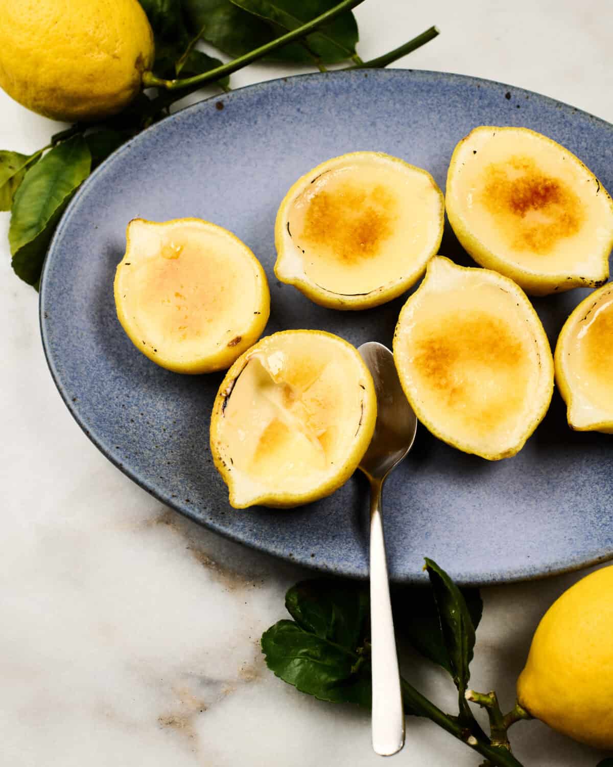 Lemon Possets on a plate with a spoon.