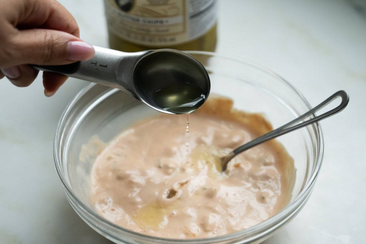 Pickle brine being added to burger sauce. 