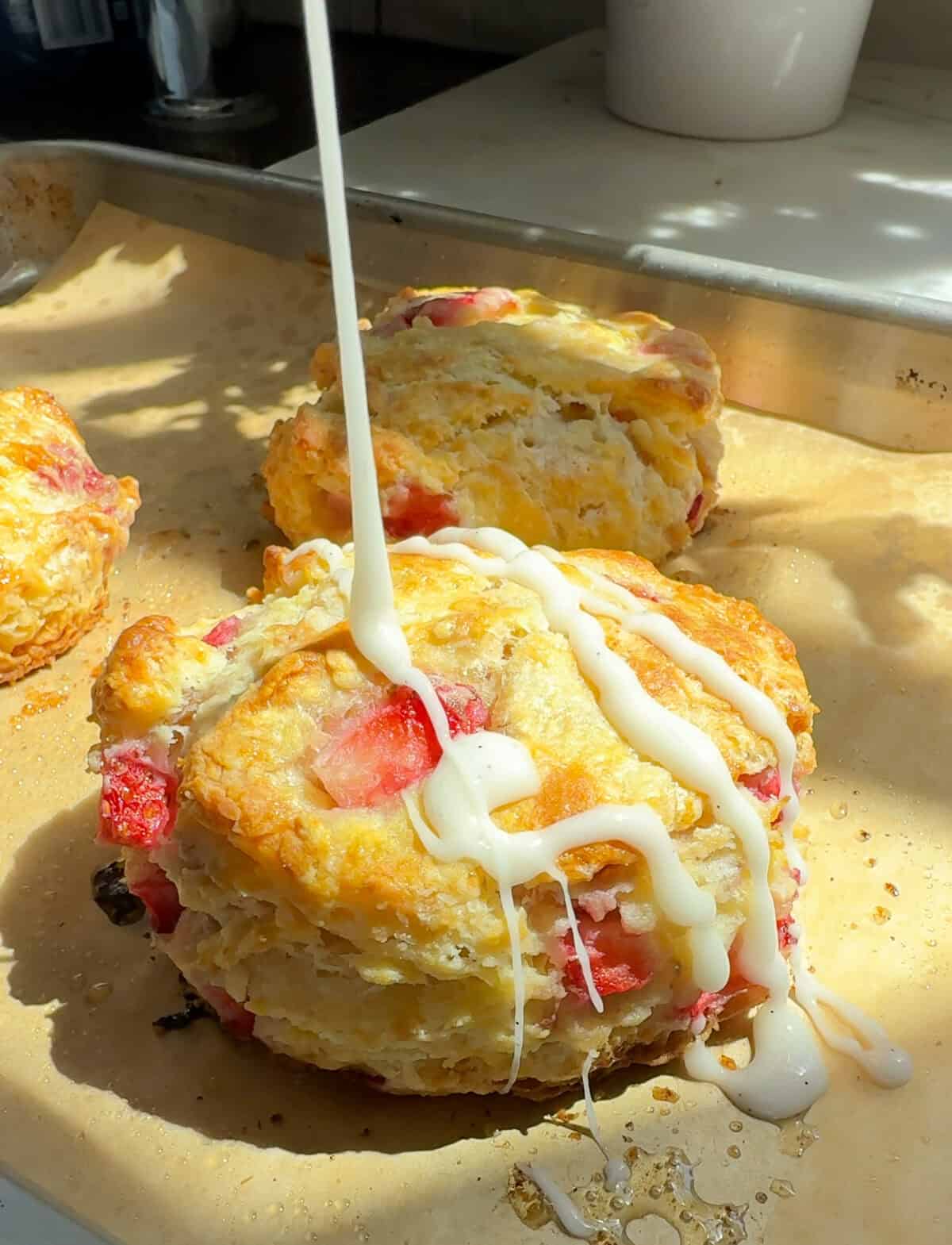 Strawberry Biscuits being drizzled with the vanilla glaze. 