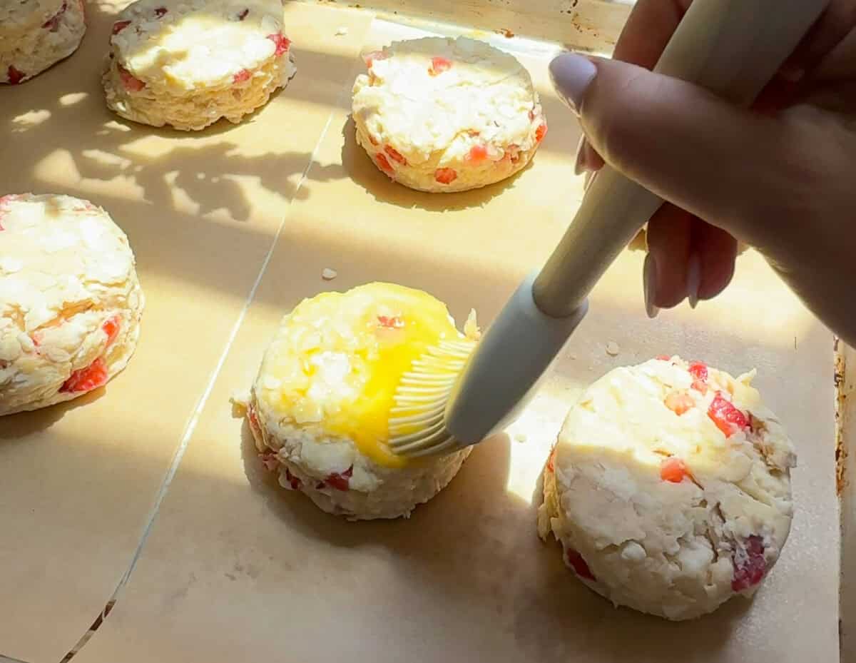Biscuits being brushed with egg wash. 