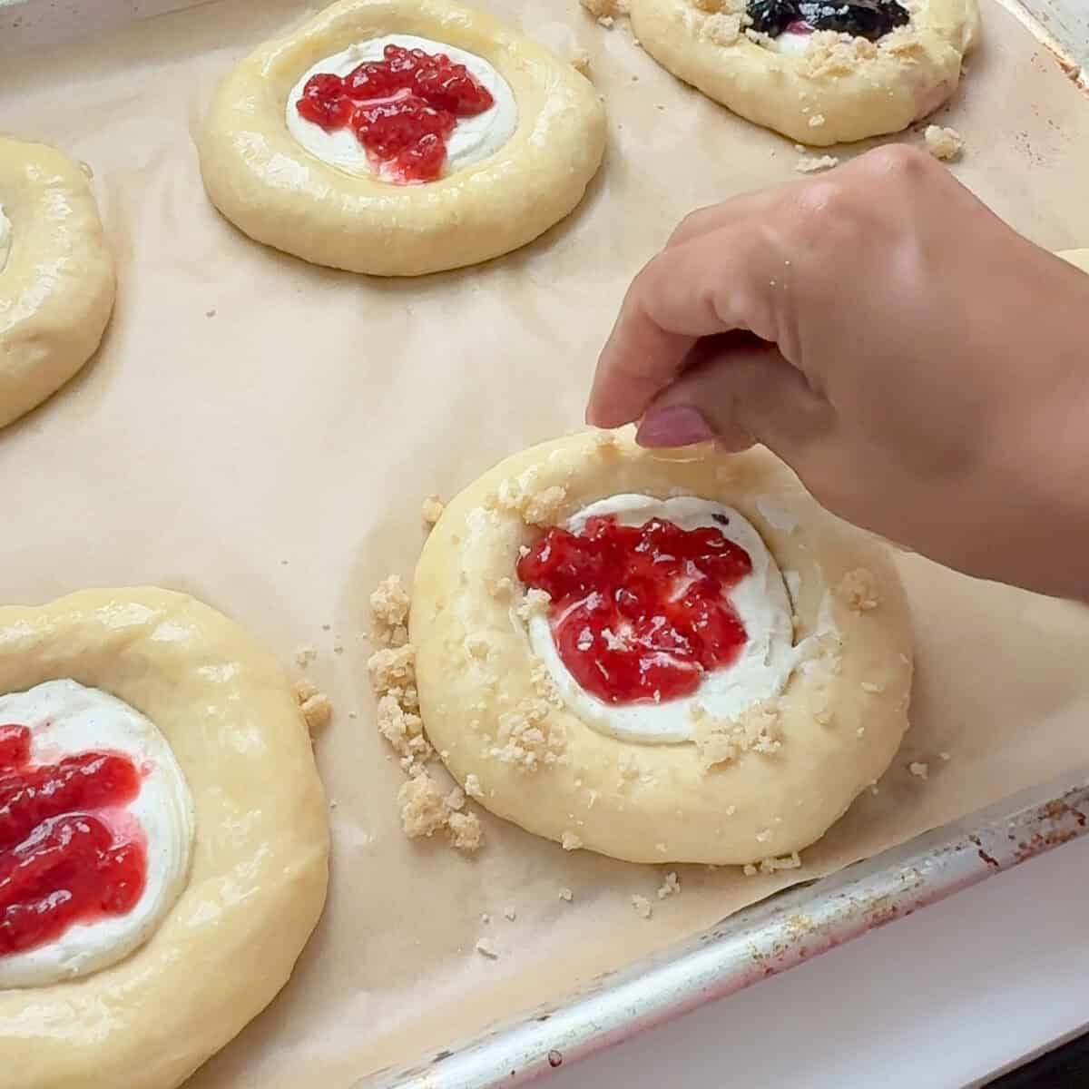 Adding streusel onto berry cheese danish.