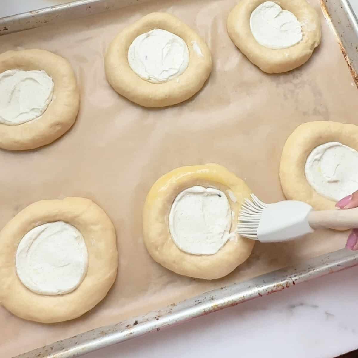 Brushing edges with egg wash.