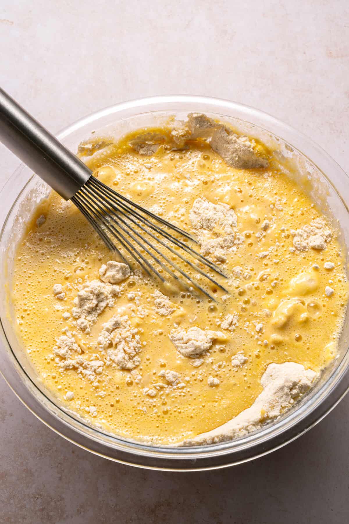 Honey cornbread muffin batter in a bowl with a whisk.
