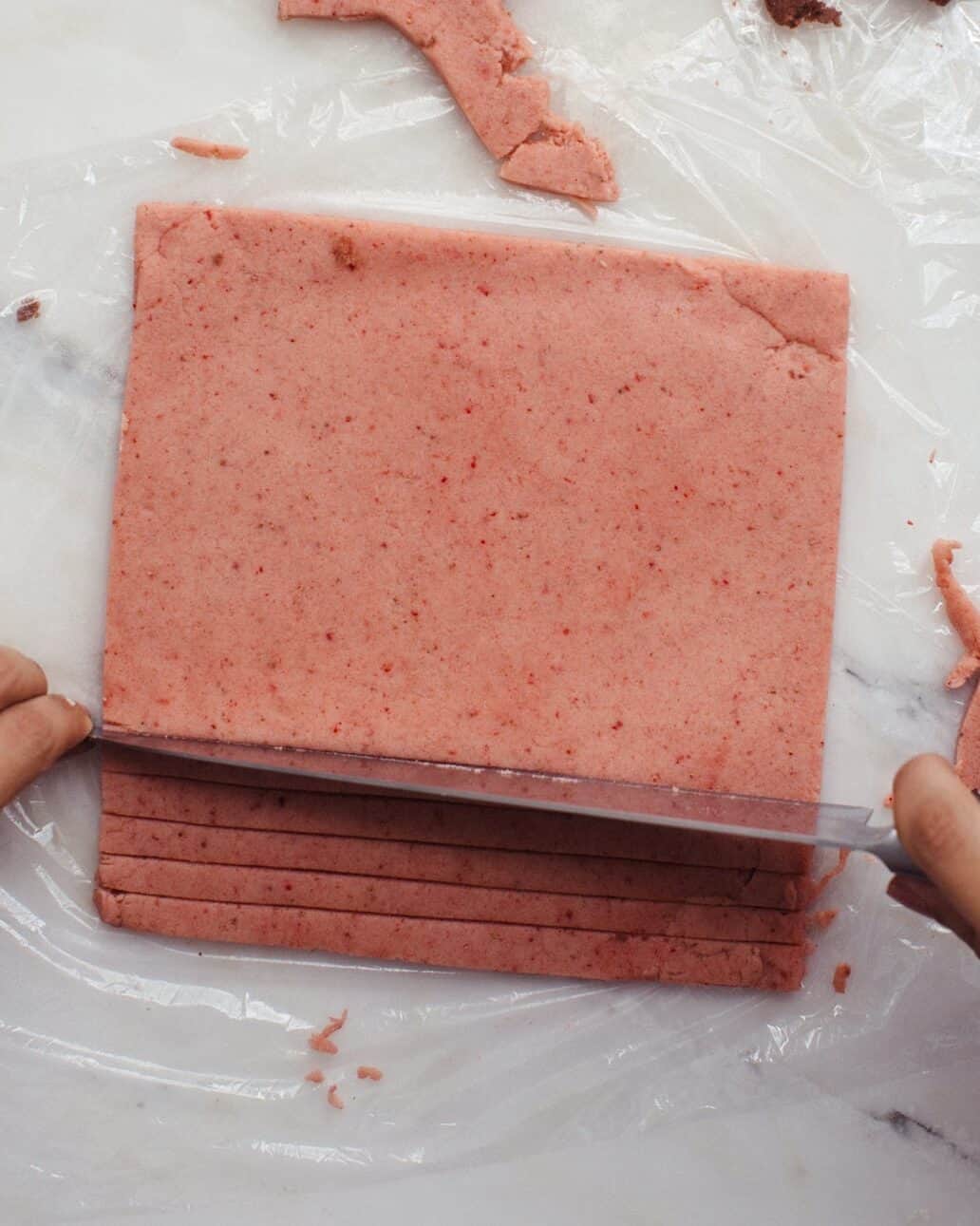 Strawberry dough being sliced.