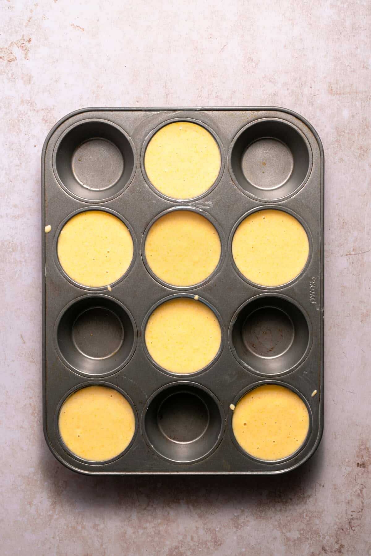 Muffin tins filled with honey cornbread muffin batter.