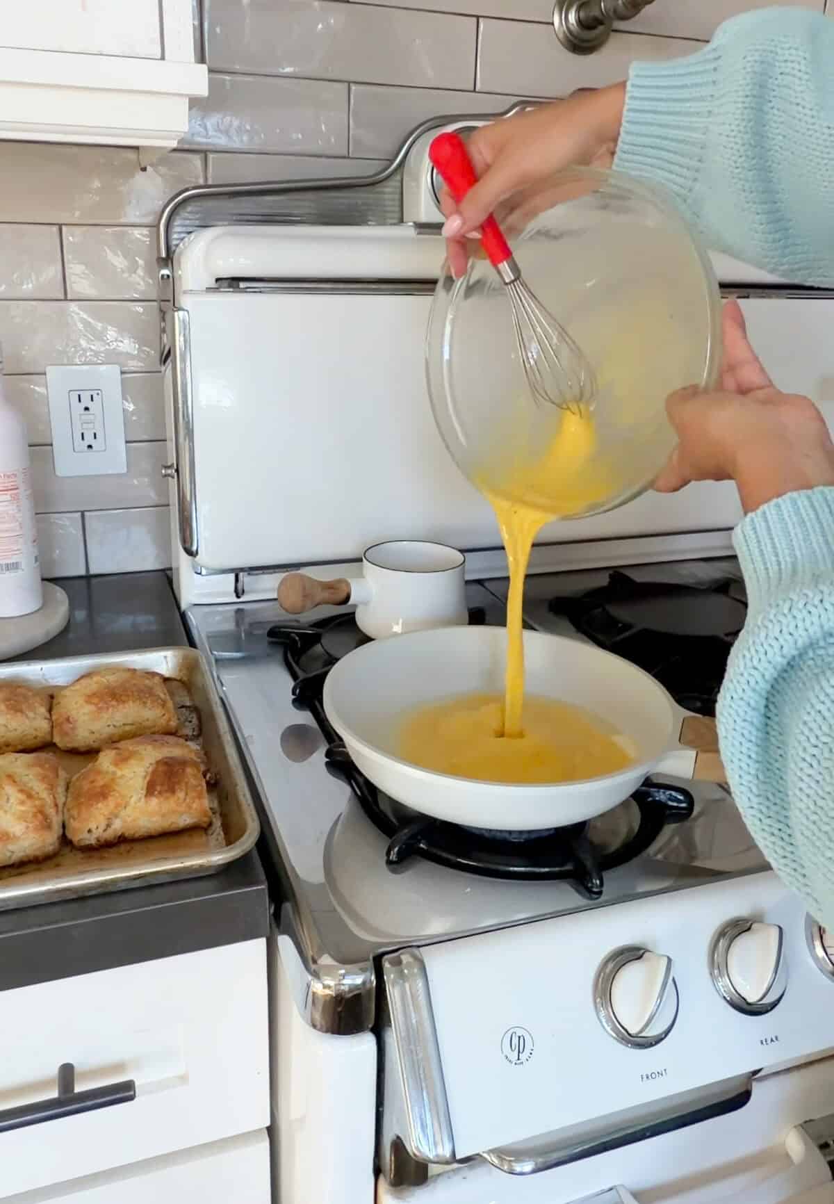 Eggs being poured into frying pan.