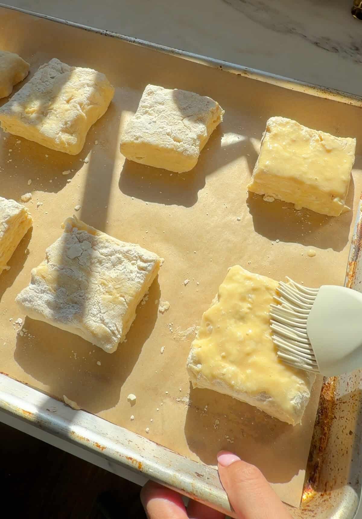 Biscuits being brushed with egg wash.
