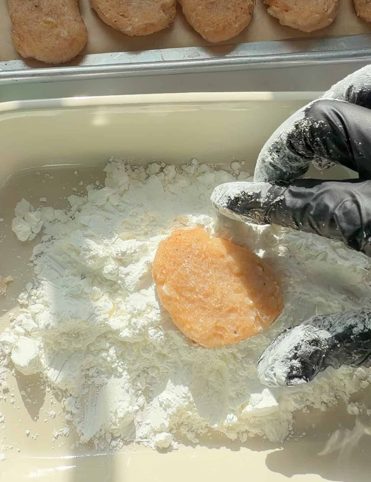 Chicken nugget being coated in cornstarch.
