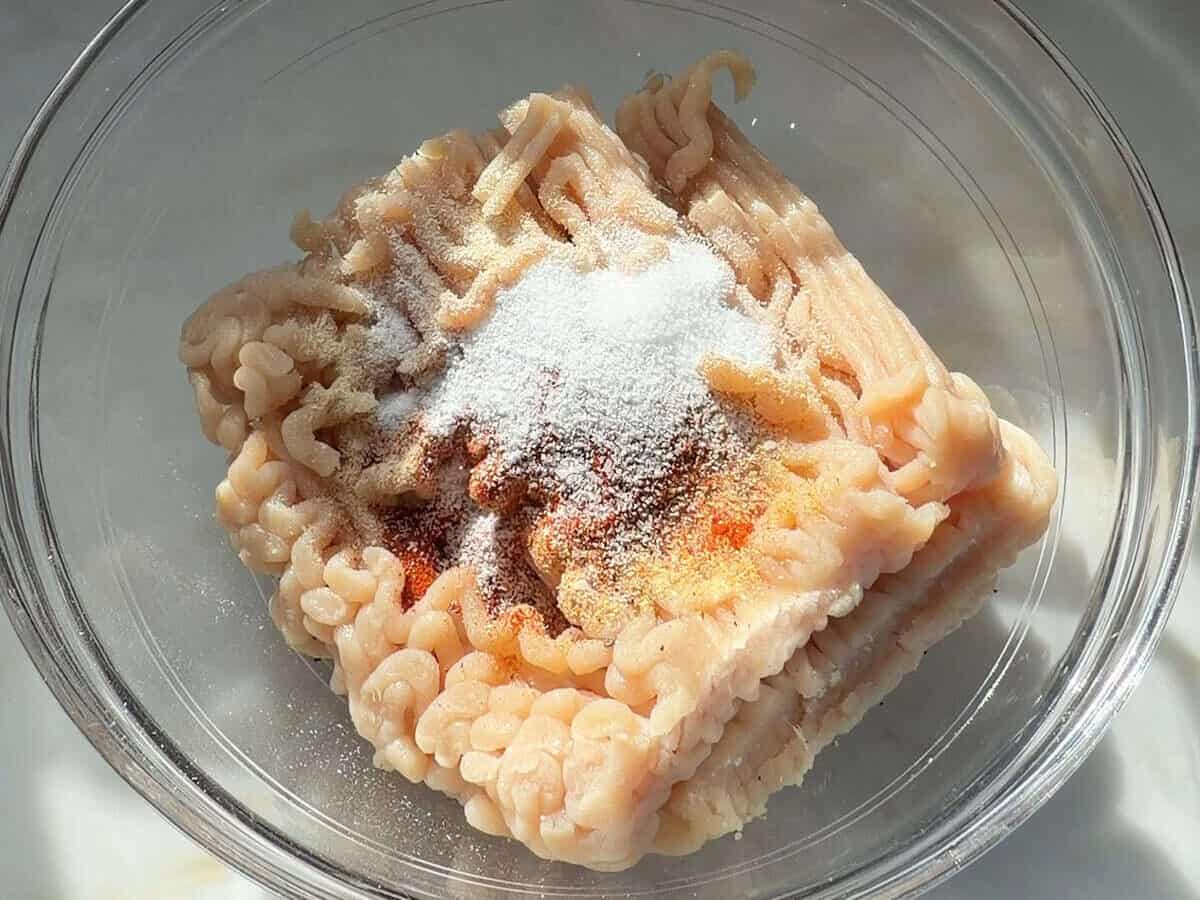 Ground chicken in a bowl with spices.