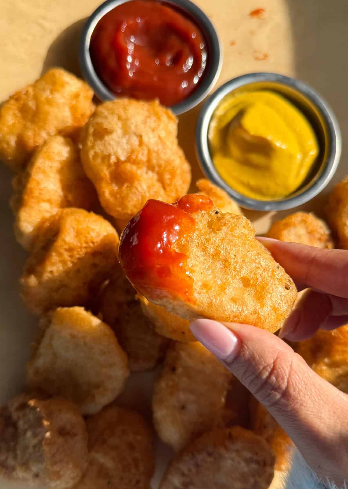 केचप में डूबा हुआ घर का बना चिकन नगेट्स।