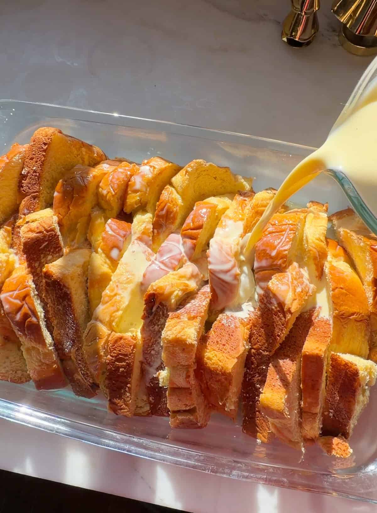 Brioche slices in baking pan with custard poured on top.