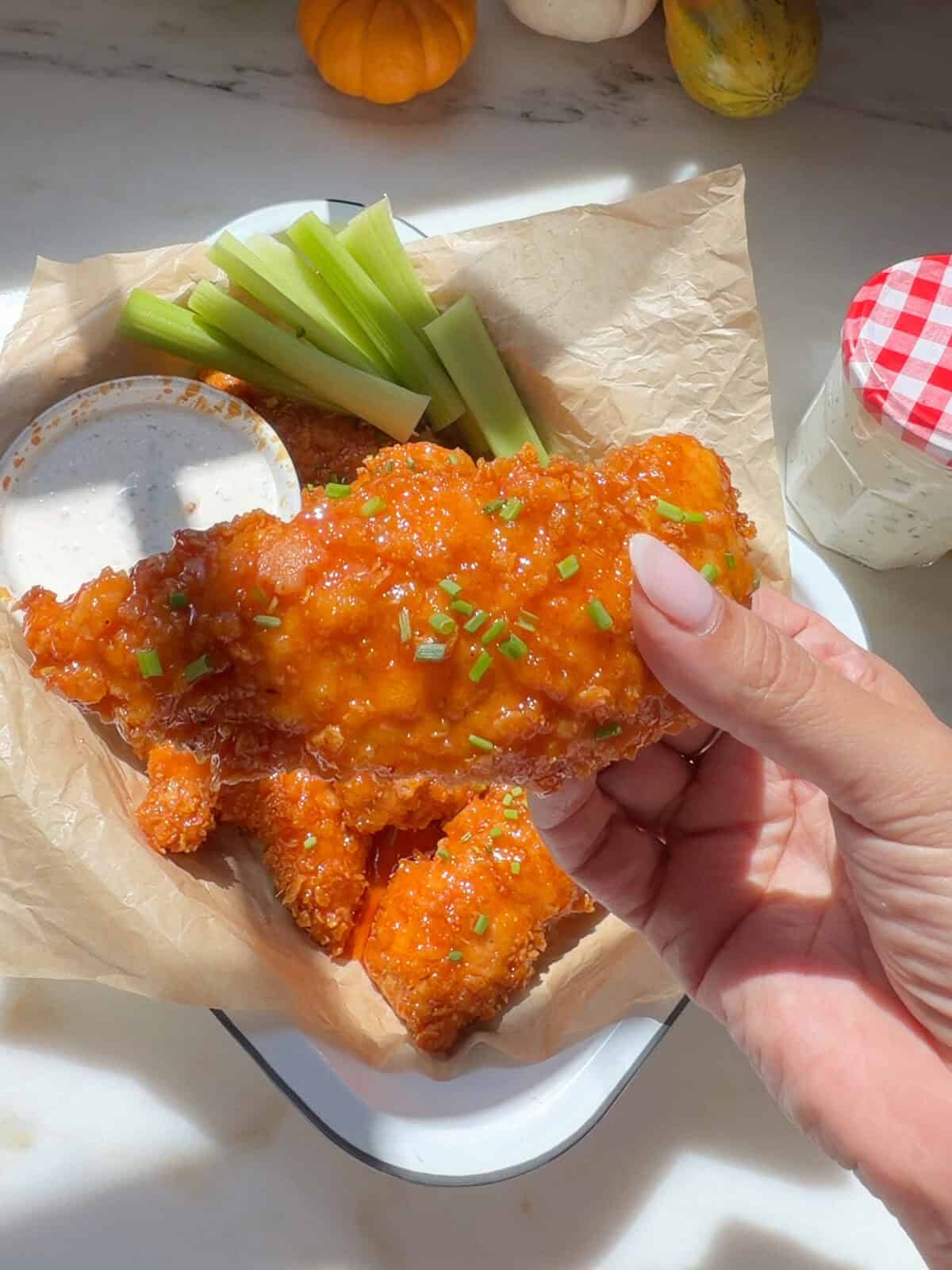 Hand holding Hot Honey Buffalo Chicken Tender.
