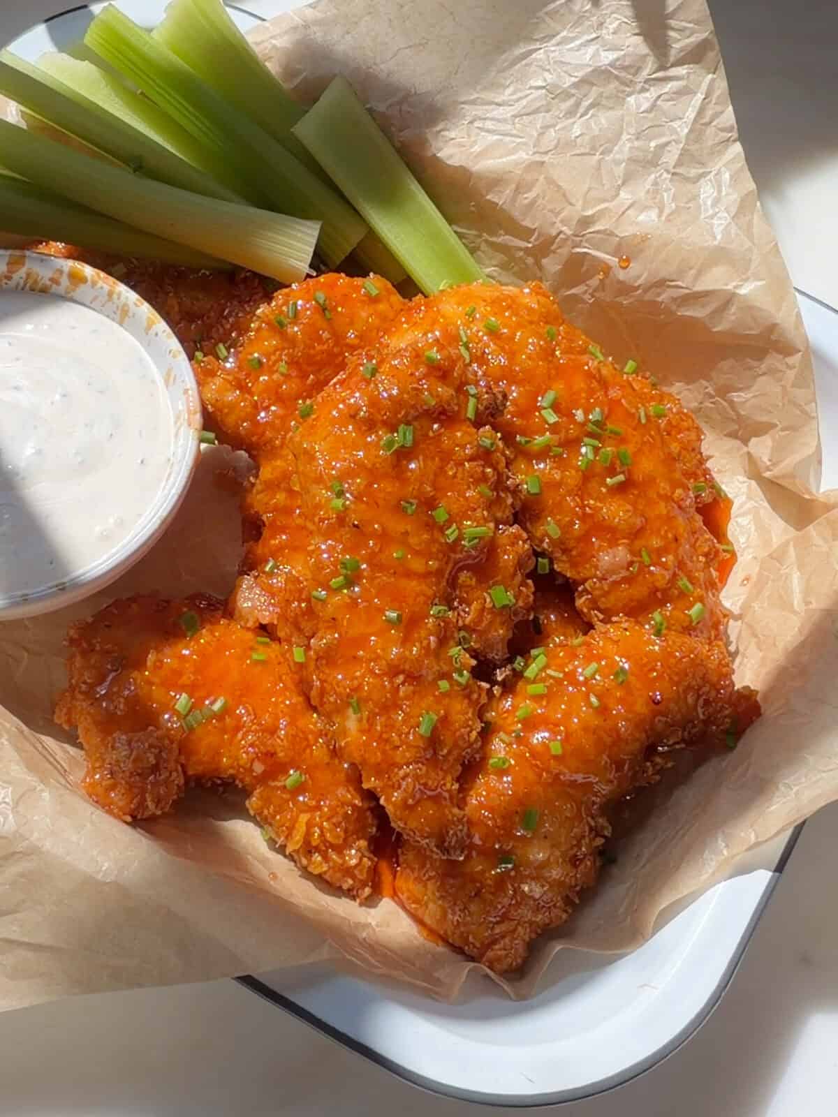 Hot Honey Buffalo Chicken Tenders with celery sticks and buttermilk ranch.