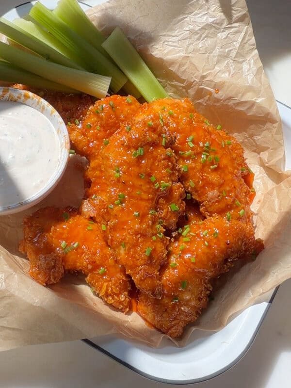 Hot Honey Buffalo Chicken Tenders with celery sticks and buttermilk ranch.