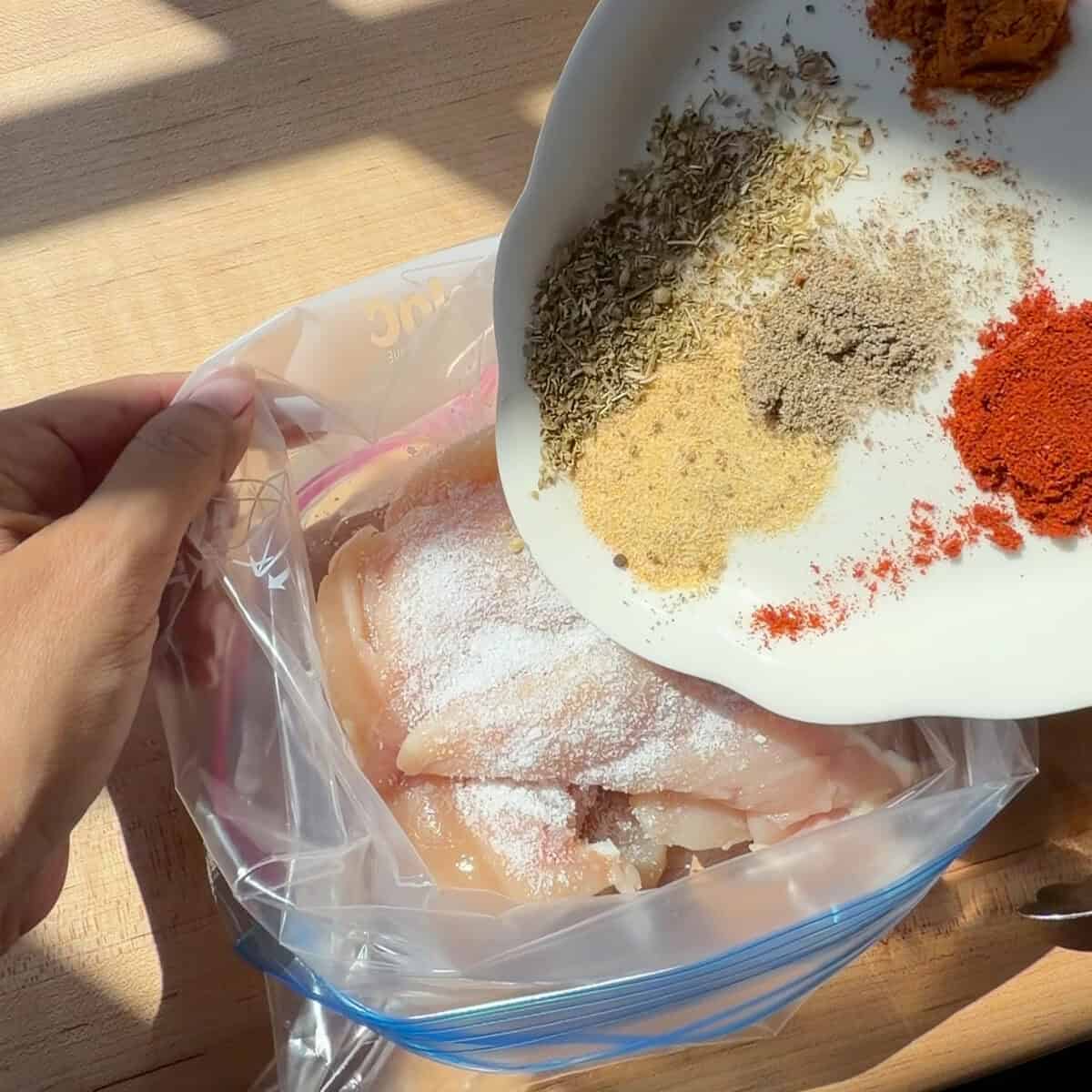 Seasoning added to chicken tenders in storage bag.