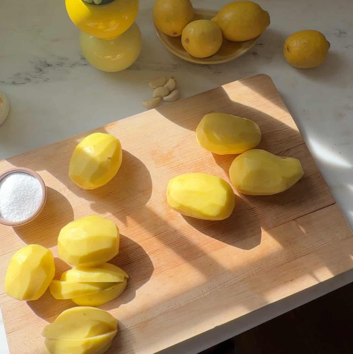 Potatoes being sliced into wedges on cutting board.