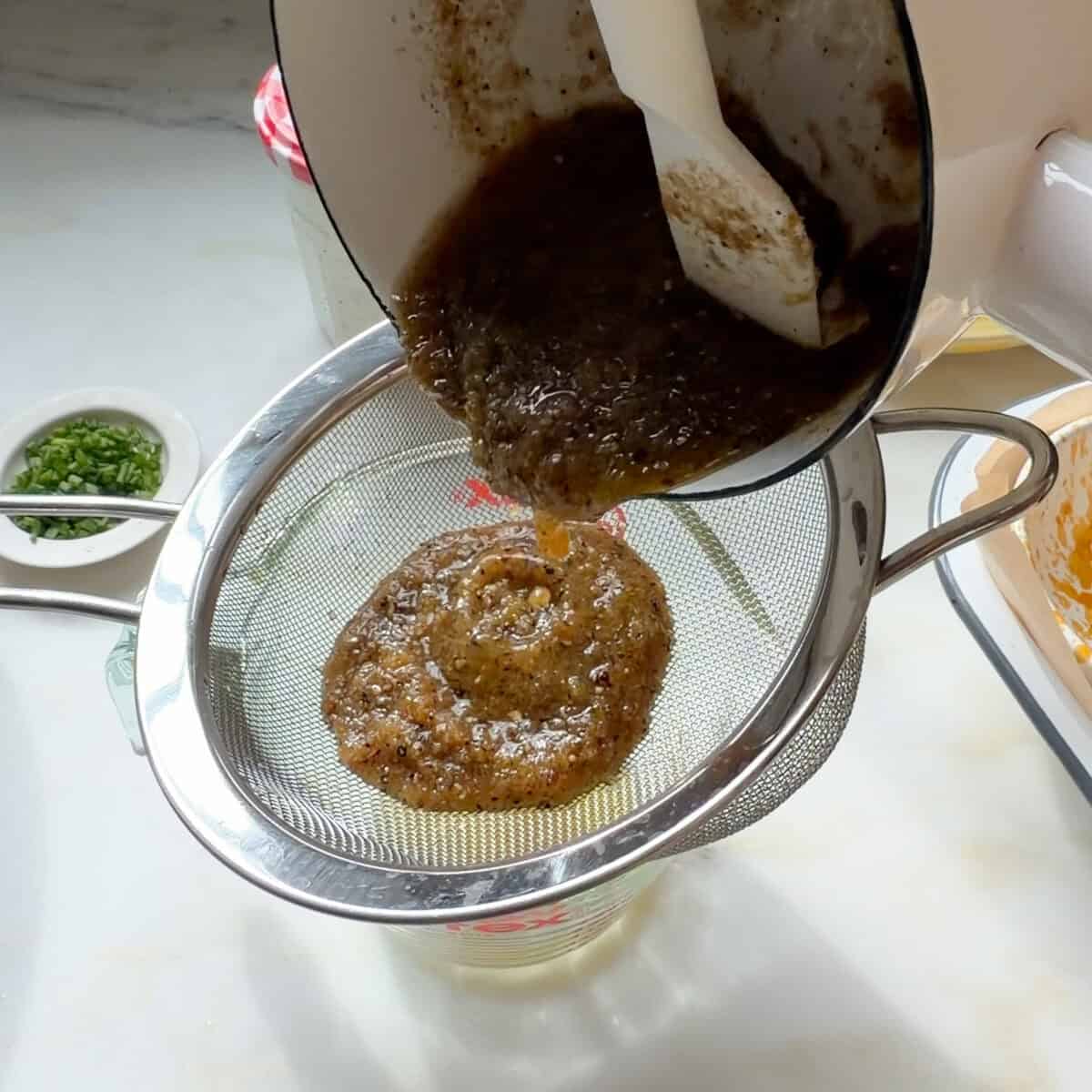Straining lemon pepper butter sauce.