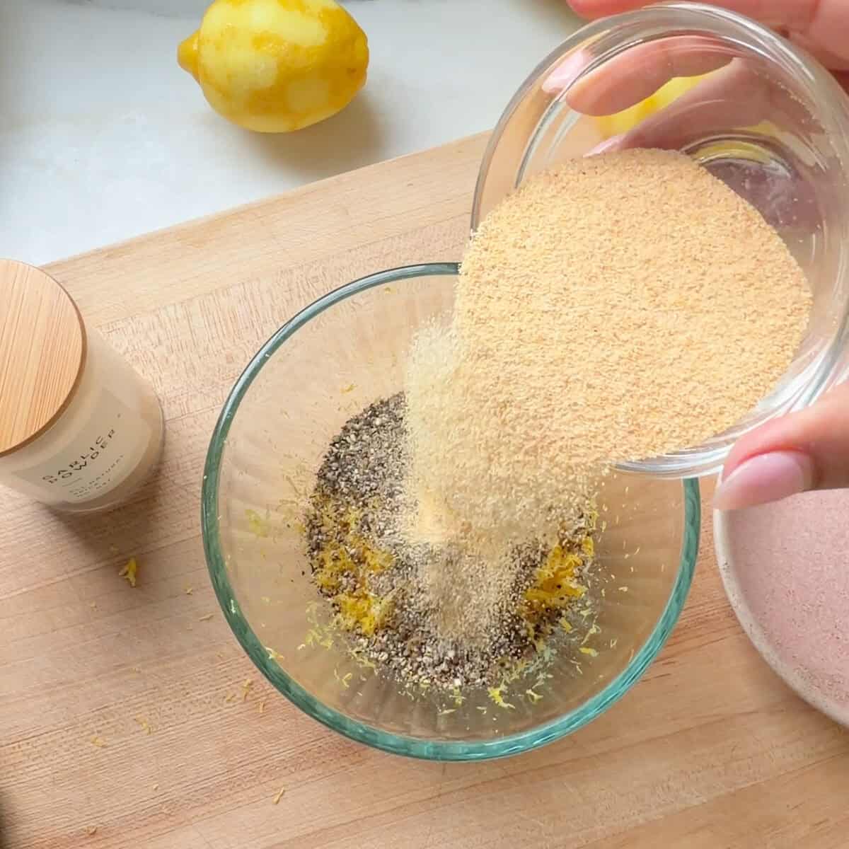 Garlic powder poured into lemon pepper seasoning.