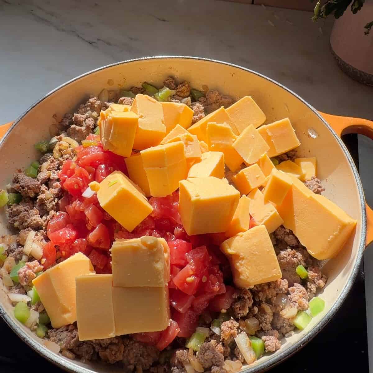 Cheese added to beef mixture in pot.