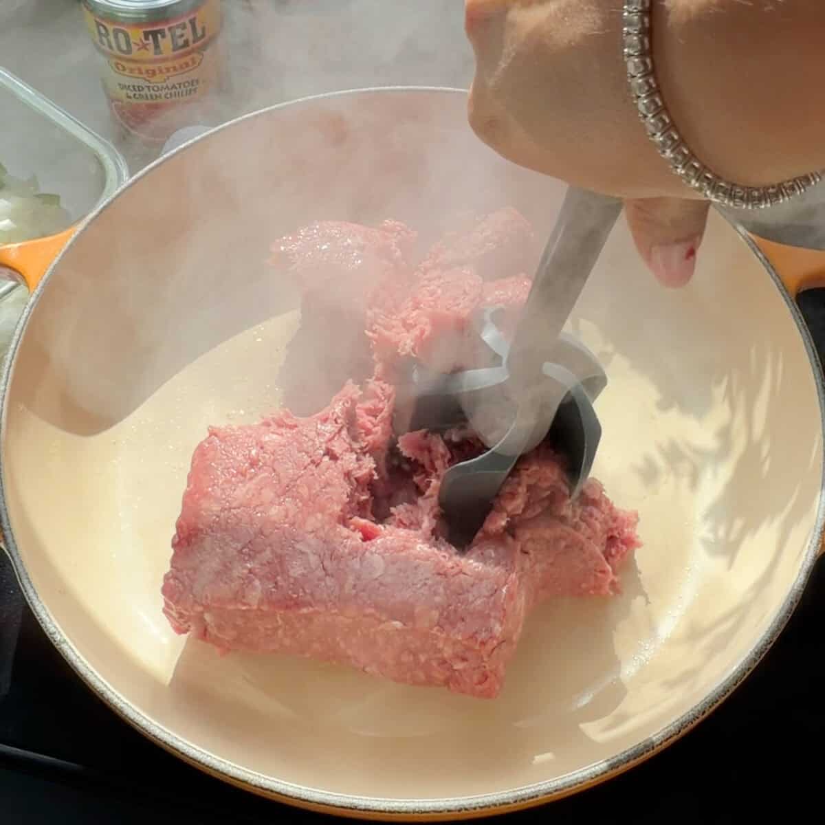 Ground beef sizzling in pan.