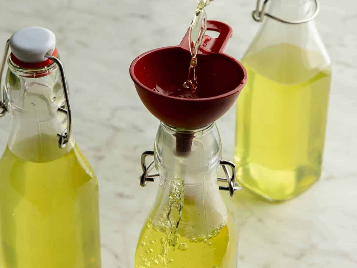 Limoncello being funneled into storage bottles.