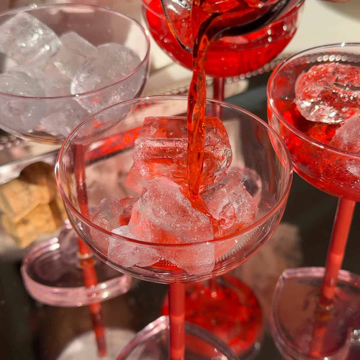 Pouring batched cocktail mixture into glass.
