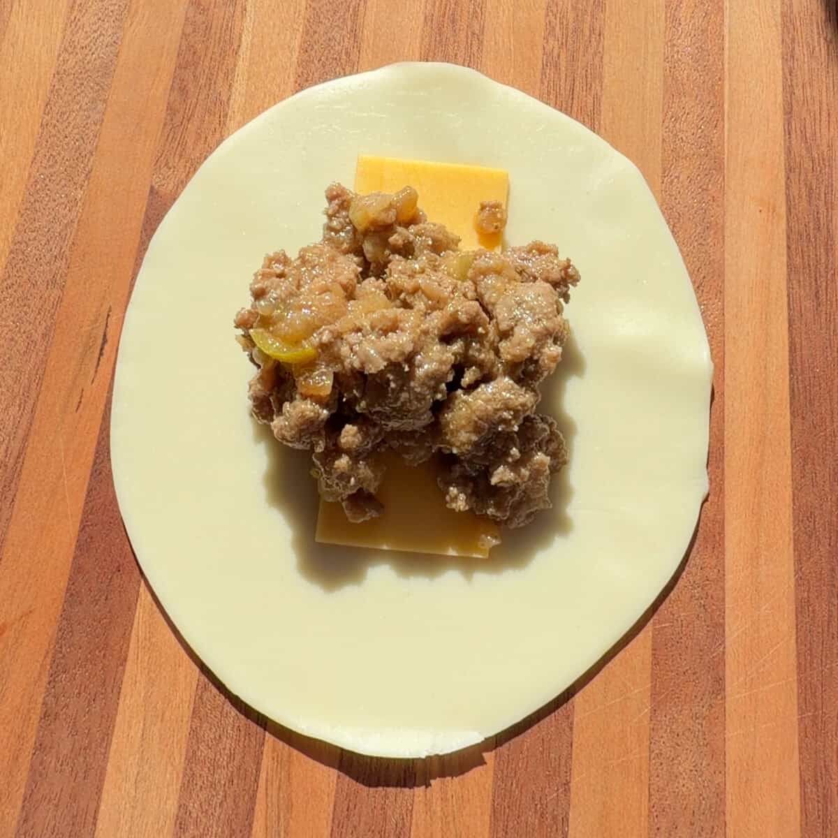 Empanada disc filled with cheese and beef mixture.