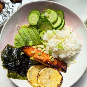 Miso Lemon Salmon with rice, cucumber, avocado, nori sheets, and grilled lemon slices.