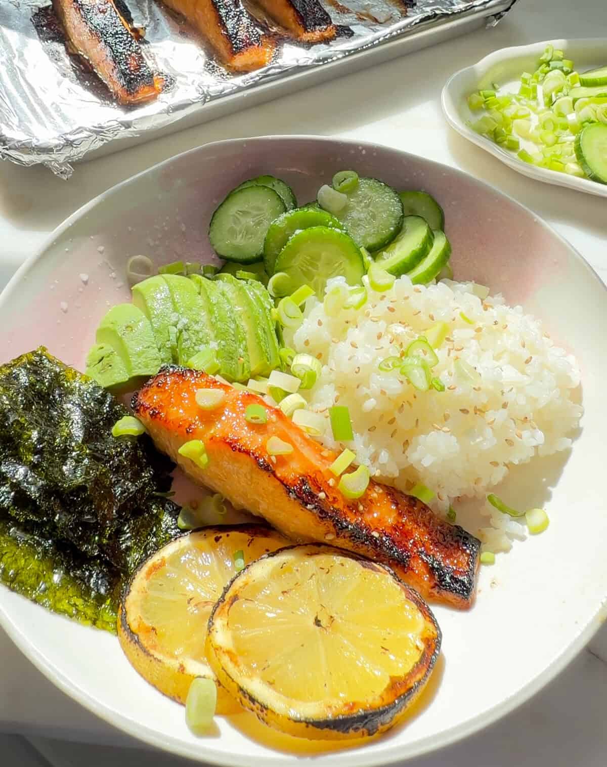 चावल, ककड़ी, एवोकैडो, नोरी शीट और ग्रिल्ड नींबू के स्लाइस के साथ मिसो लेमन सैल्मन।