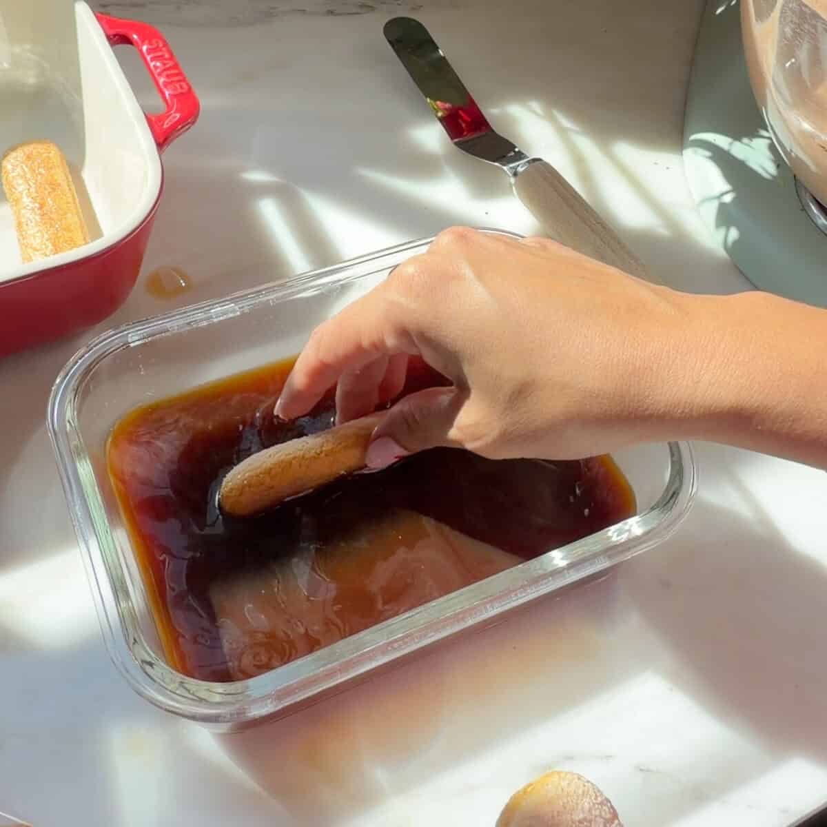 Dipping ladyfinger in coffee mixture.