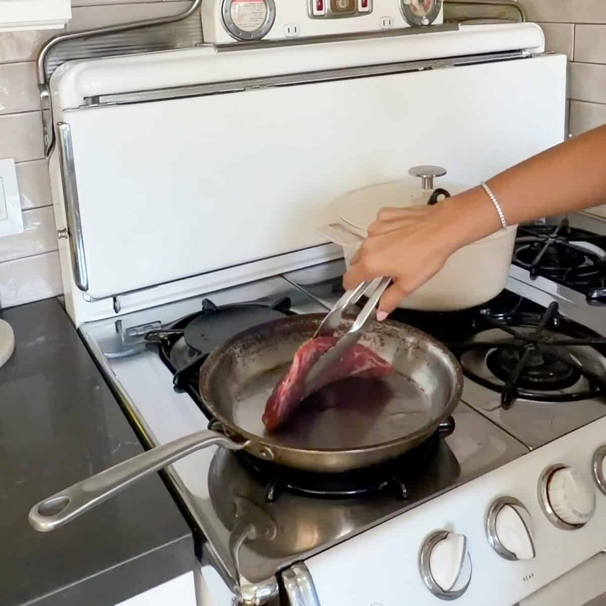 Searing steak in hot skillet.