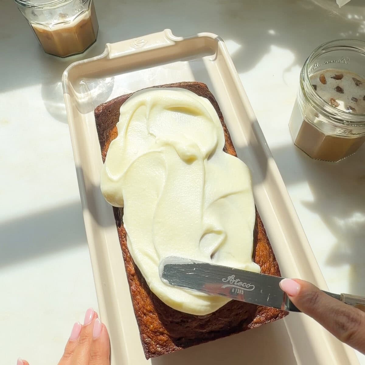 Cream cheese frosting spread on top of Butter Pecan Banana Bread.