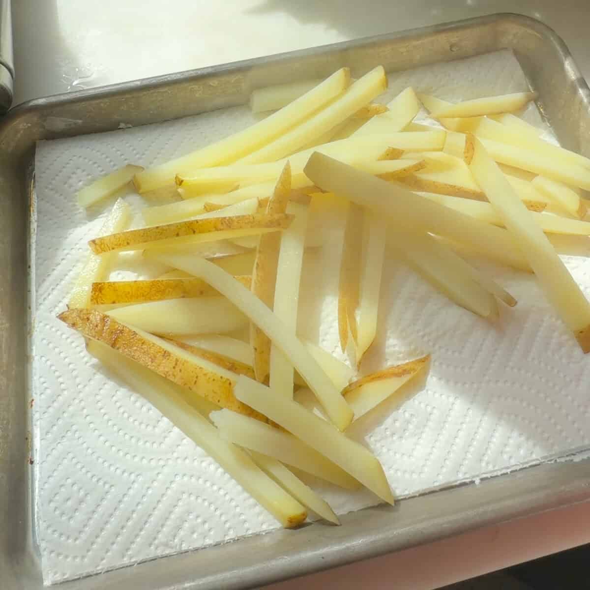 Boiled and par-cooked French fries on baking sheet.