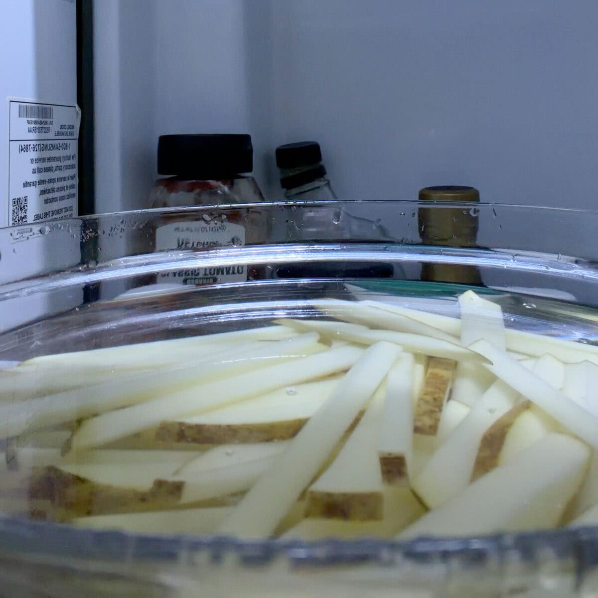 French fry cut potatoes soaking in water in the refrigerator.