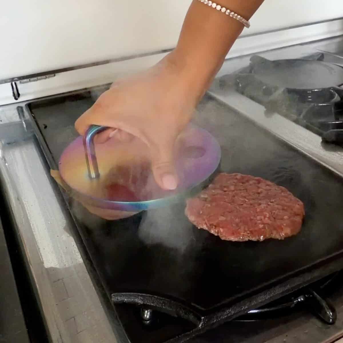 Pressing burgers on flat top griddle.