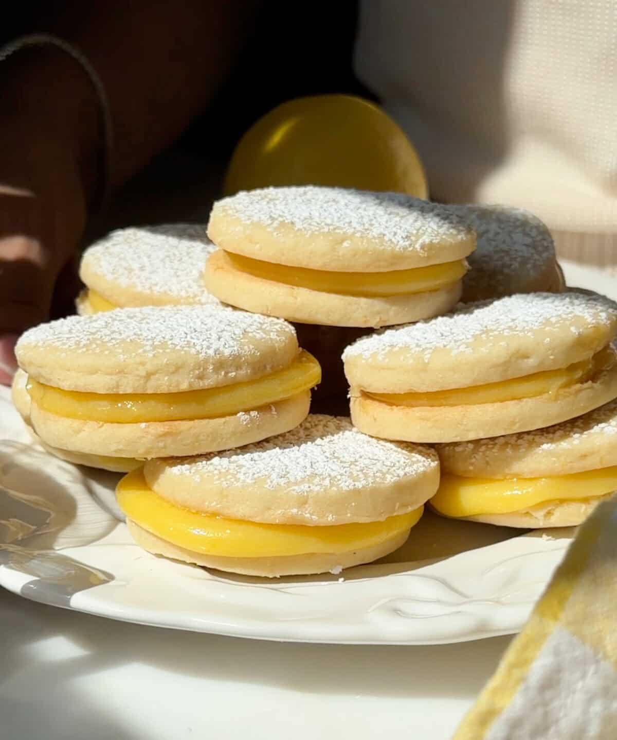 Lemon Alfajores stacked on a plate.