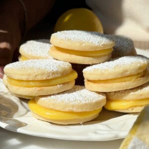 Lemon Alfajores stacked on a plate.