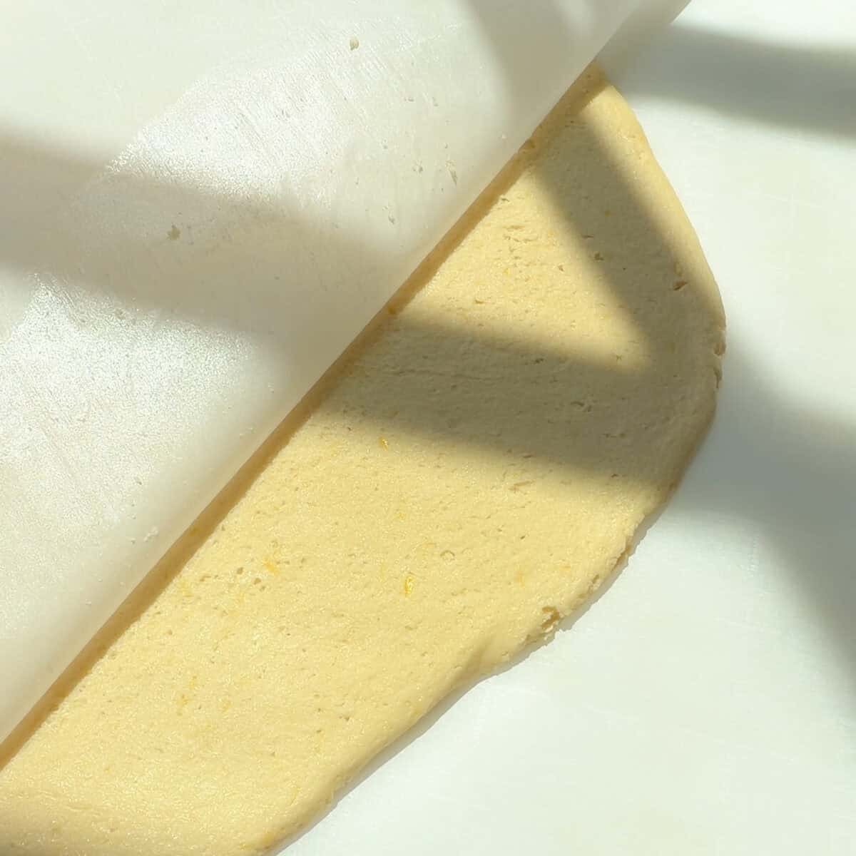Rolled out cookie dough between two sheets of parchment paper.